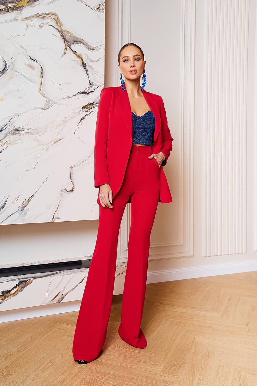 Woman in a red suit standing in a room with a marble wall.