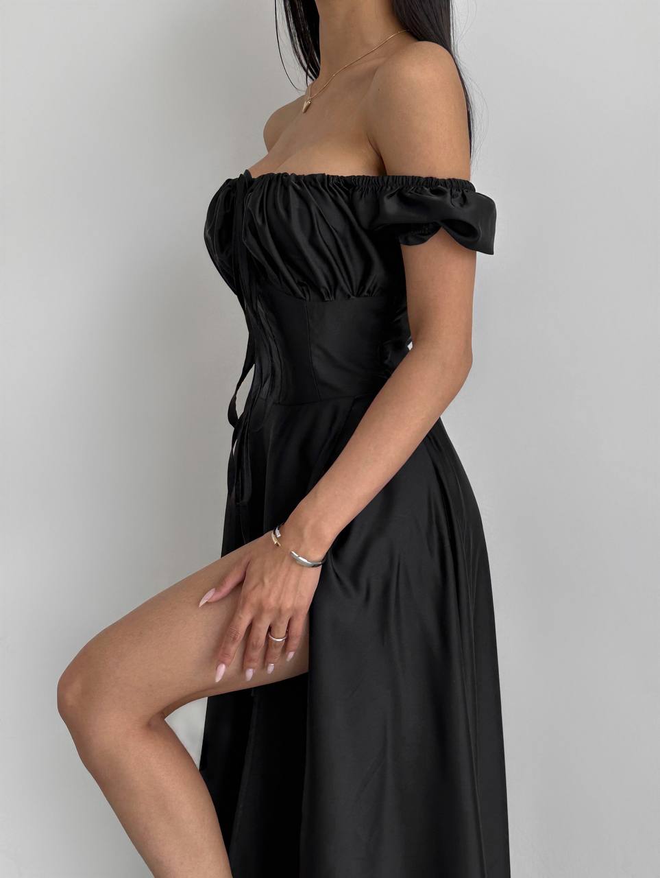 Black off-shoulder dress worn by a person on a plain background