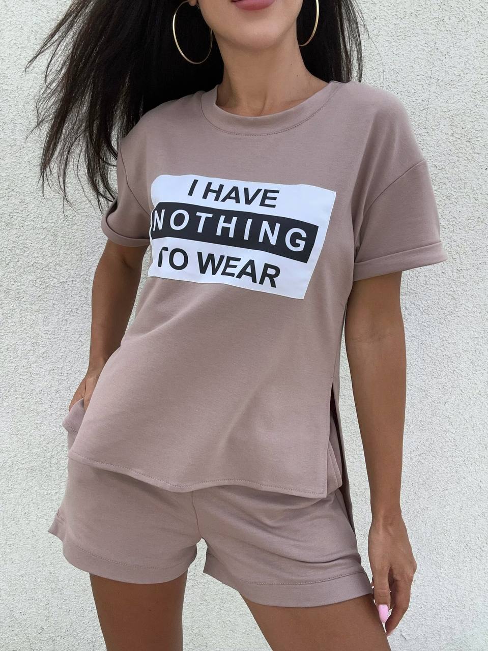 Person wearing a mauve t-shirt with text and matching shorts against a neutral background