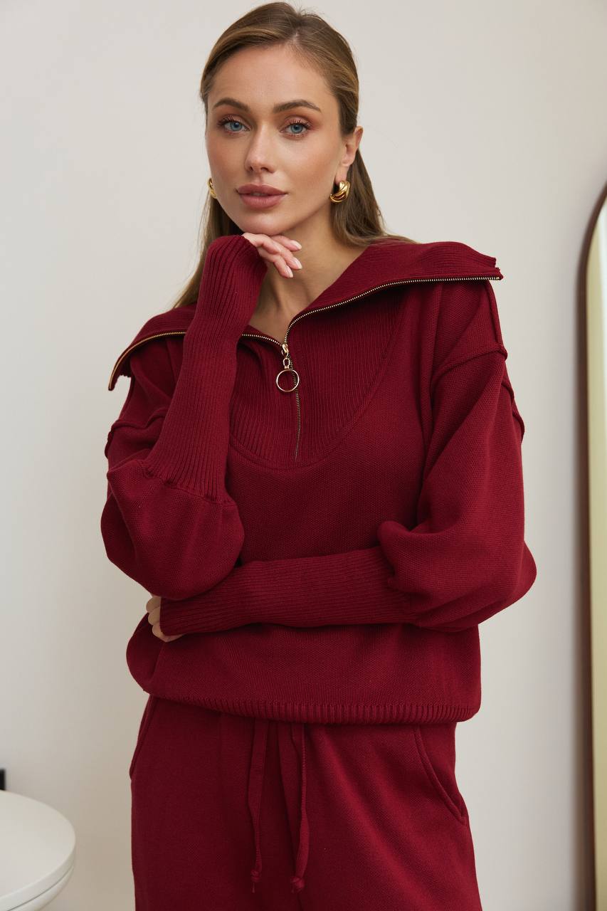 Woman wearing a burgundy tracksuit against a plain background