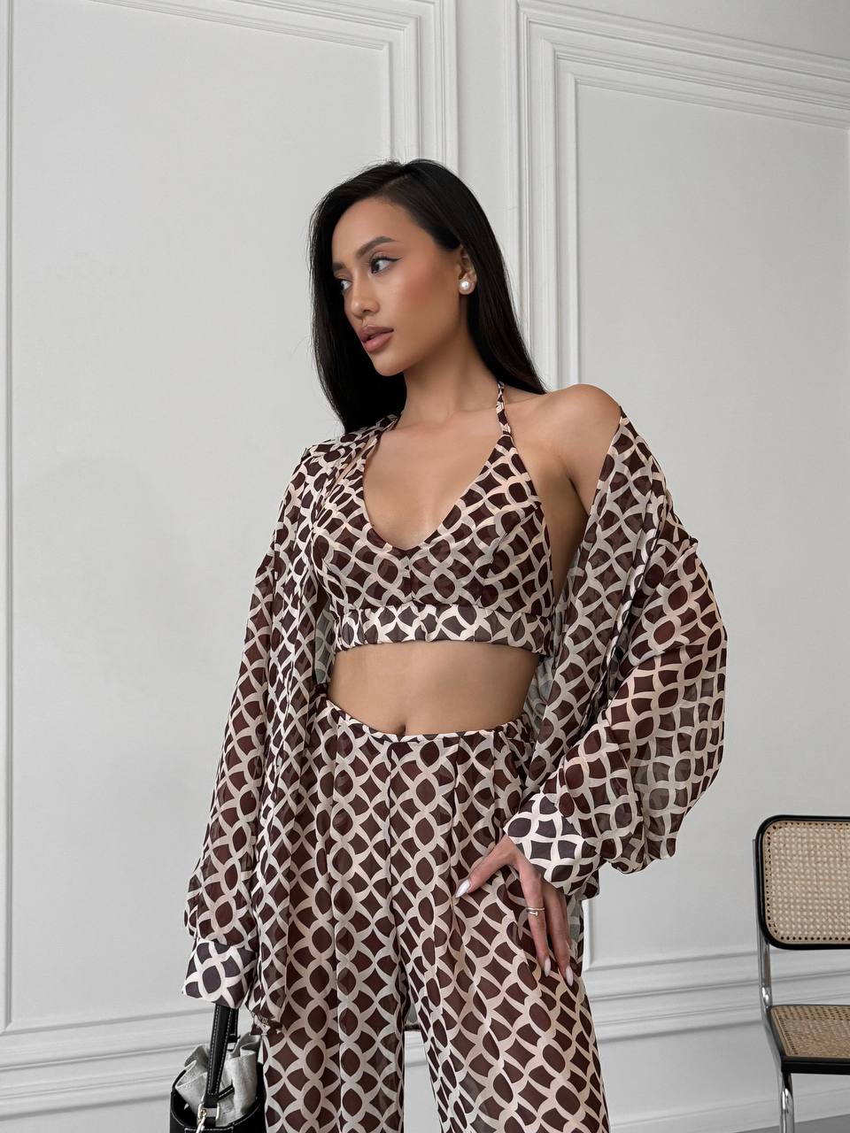Woman wearing a patterned outfit against a white wall