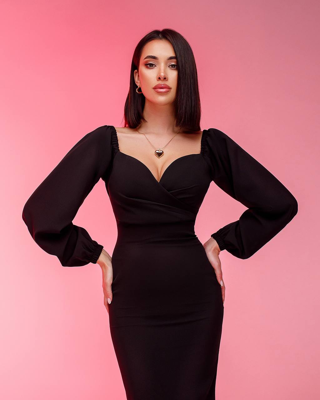 Woman wearing a black dress against a pink background