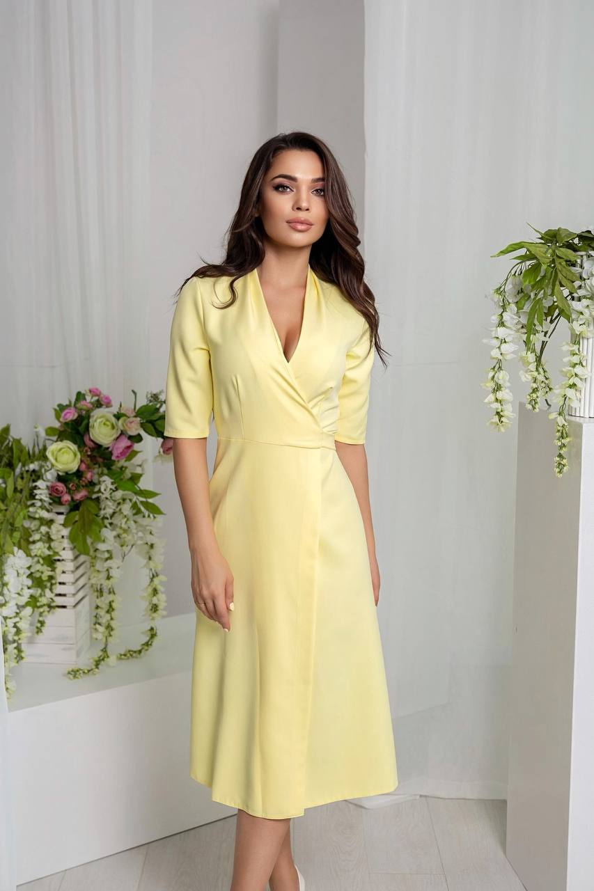 Woman wearing a yellow dress standing in a room with white walls and decorative plants.