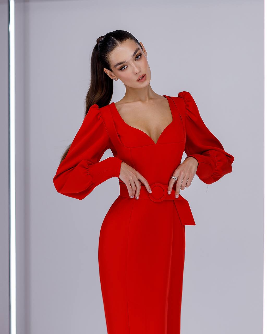 Woman wearing a red dress with puffed sleeves against a gray background