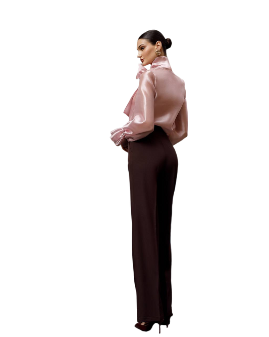 Woman wearing a pink blouse and dark pants on a white background