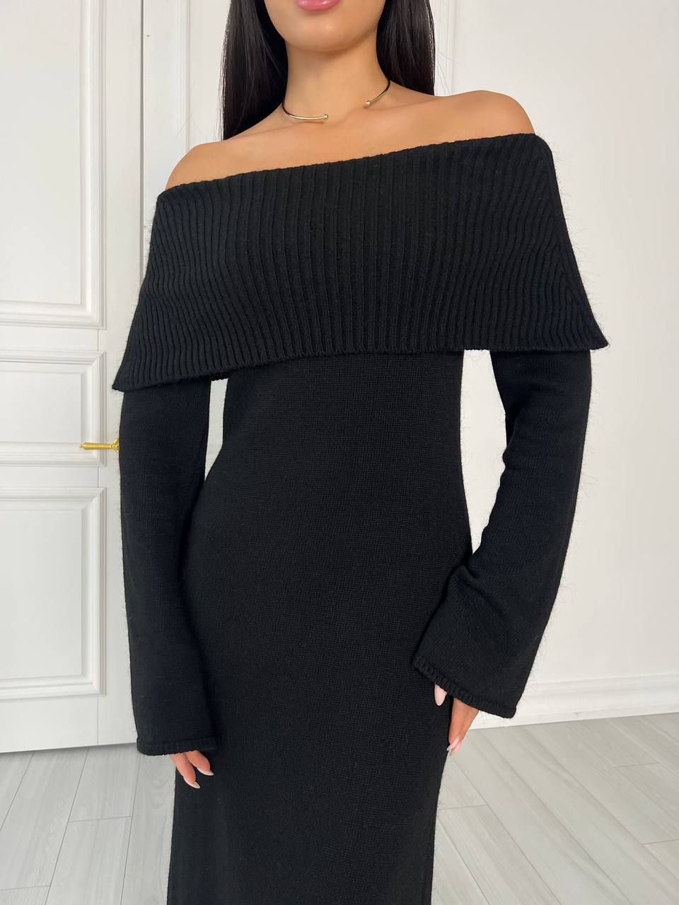 Black off-shoulder dress worn by a model against a white background