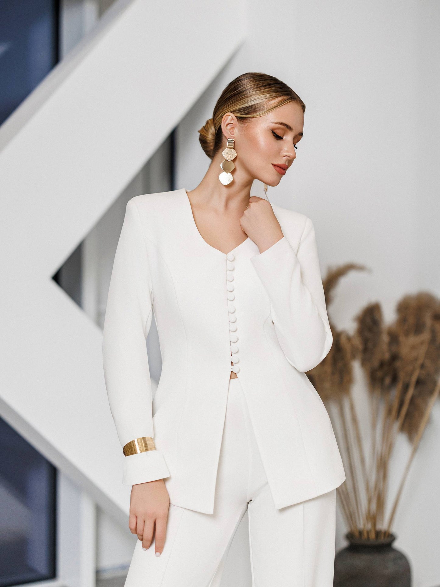 Woman wearing a white outfit with gold accents in an indoor setting