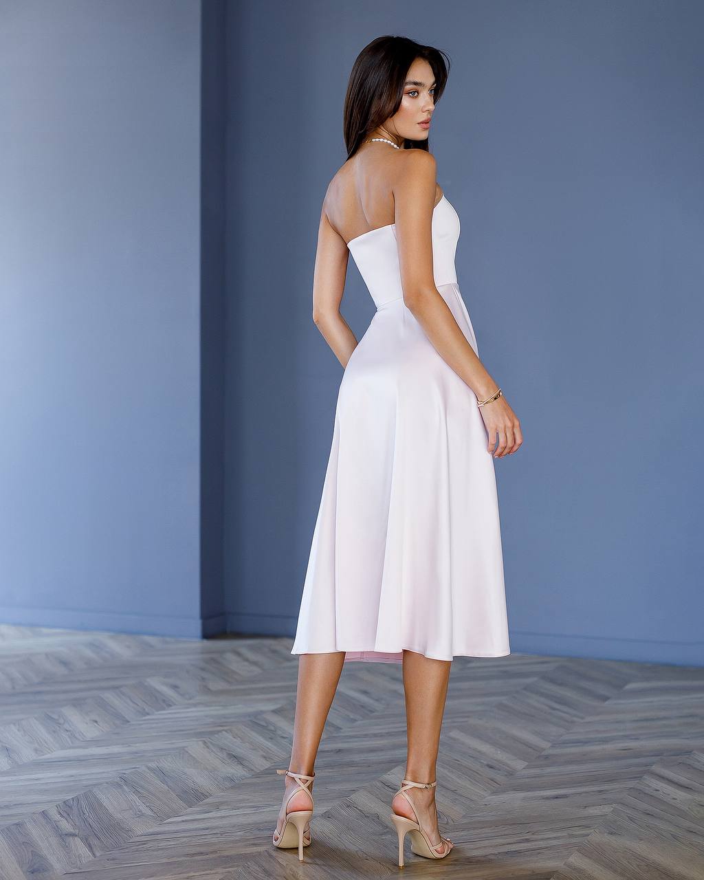 Woman wearing a white dress against a blue wall