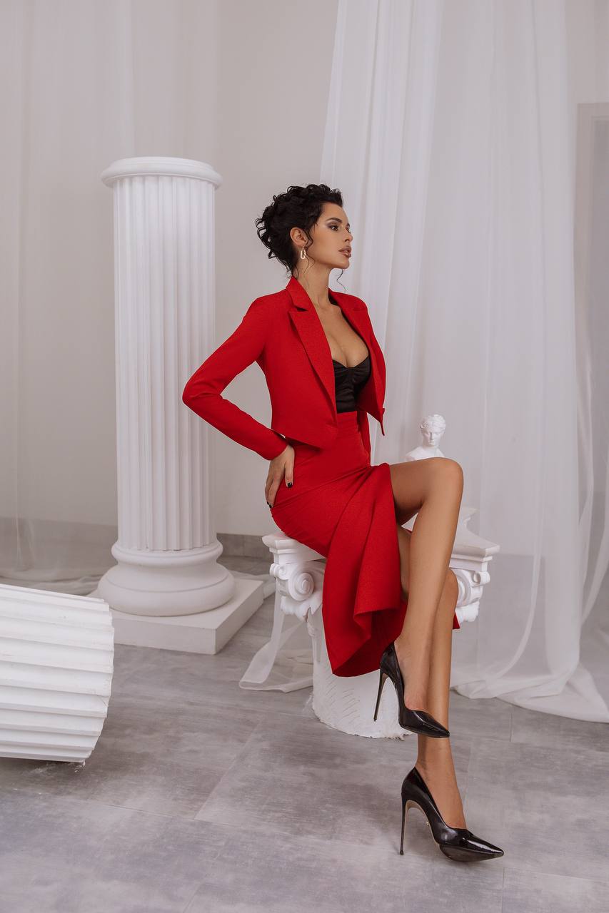 Woman in a red outfit sitting on a white chair with classical columns in the background