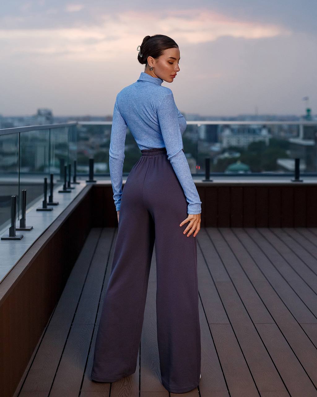 Woman standing on a rooftop deck with a cityscape in the background