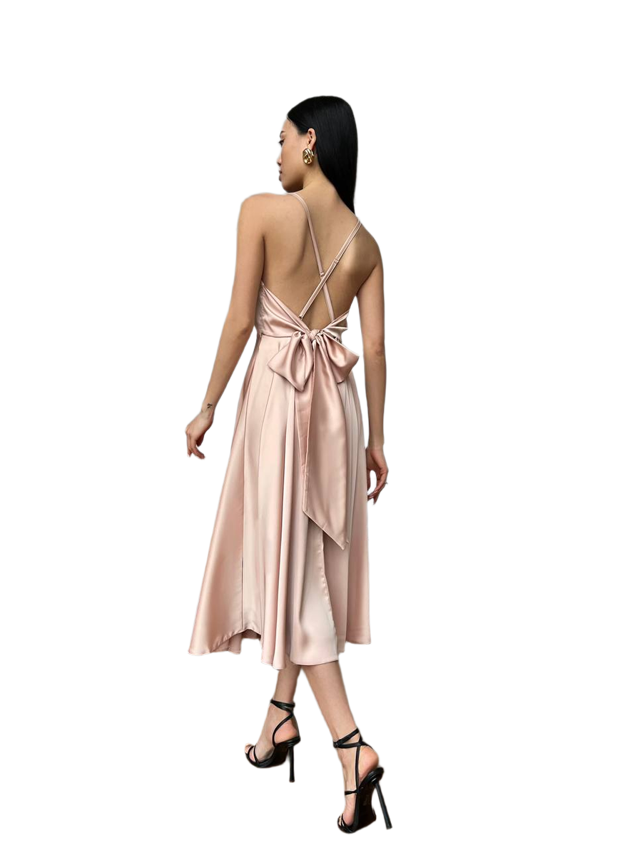Woman wearing a pink satin dress with a bow detail on a white background