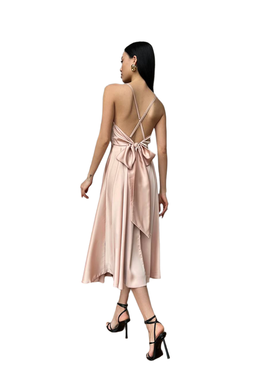 Woman wearing a pink satin dress with a bow detail on a white background