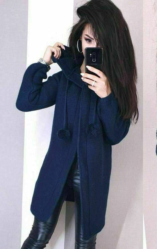 Woman wearing a blue coat taking a mirror selfie.