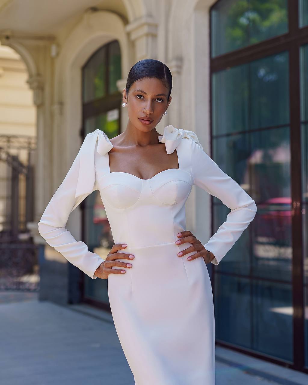 Woman in a white dress standing in front of a building
