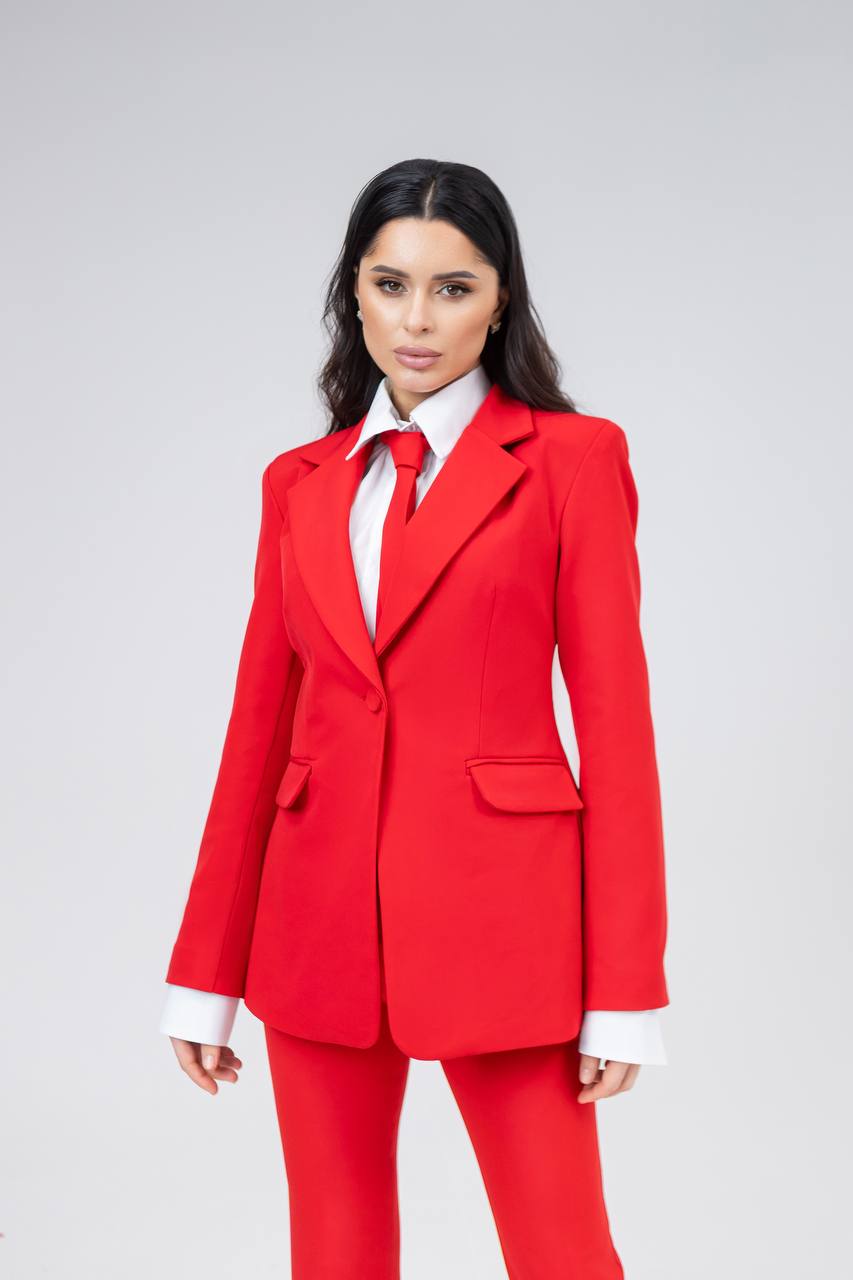 Woman wearing a red suit with a white shirt on a gray background