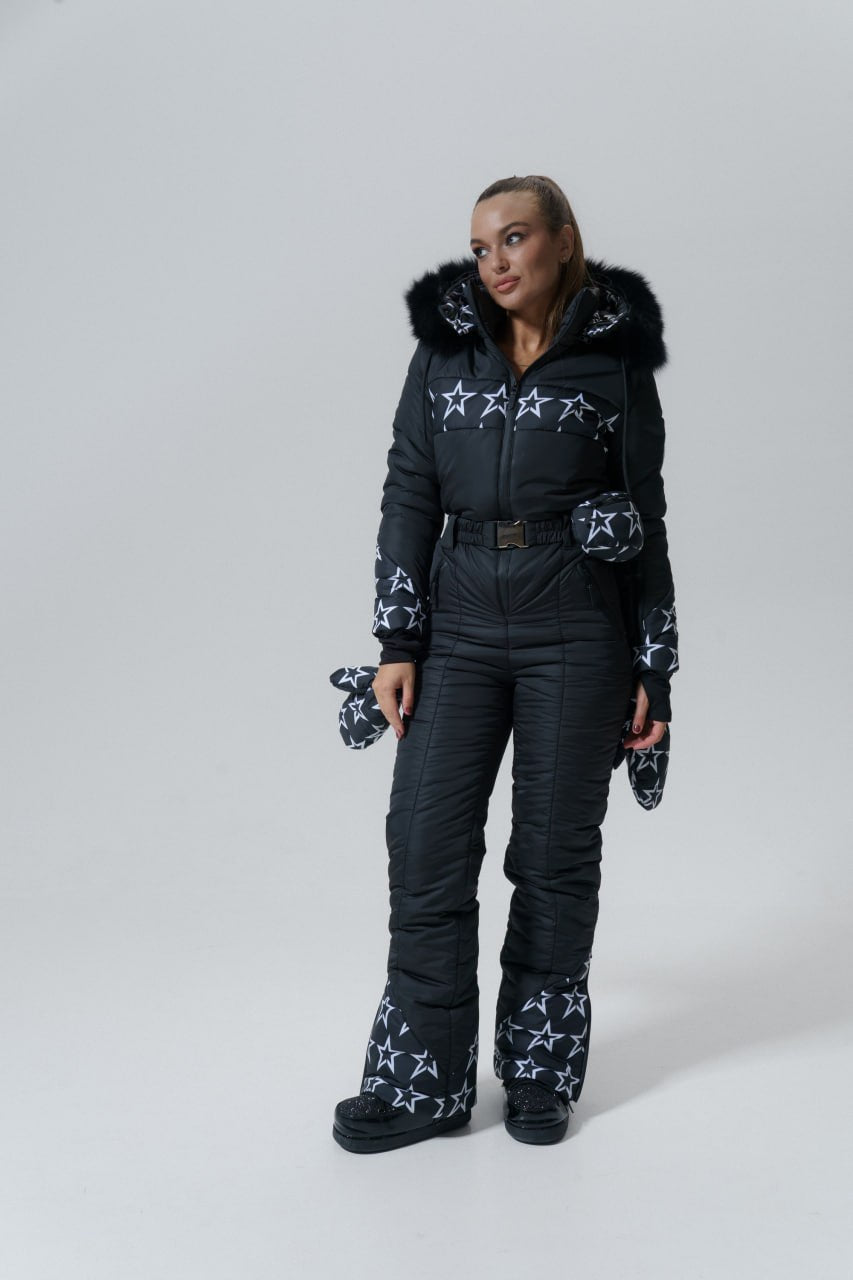 Person wearing a black snowsuit with star patterns on a white background