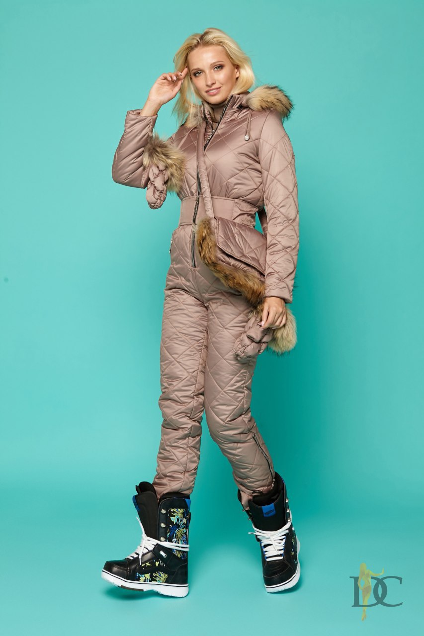 Woman wearing a beige winter outfit with fur accents on a teal background