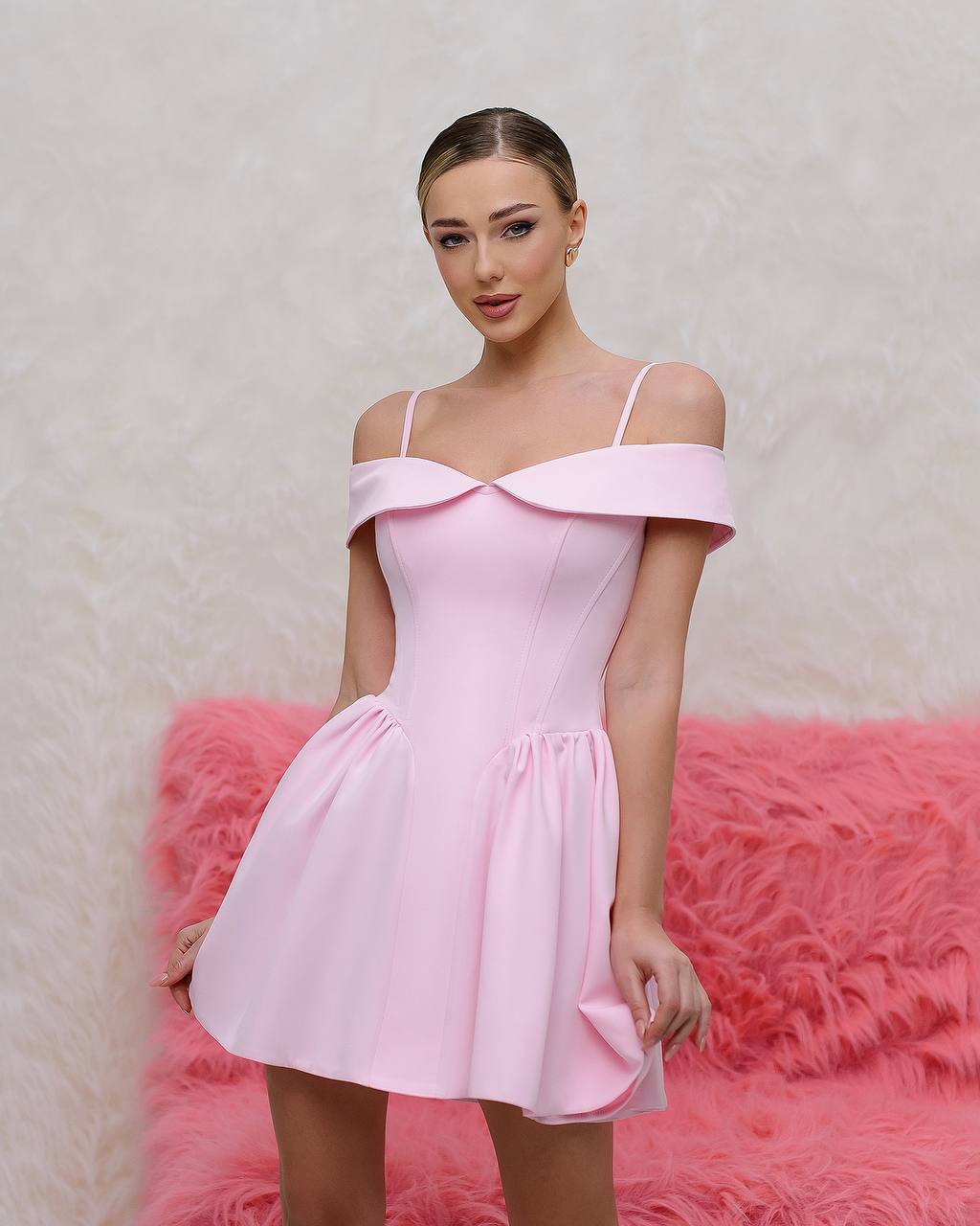 Woman wearing a pink off-shoulder dress against a pink textured background