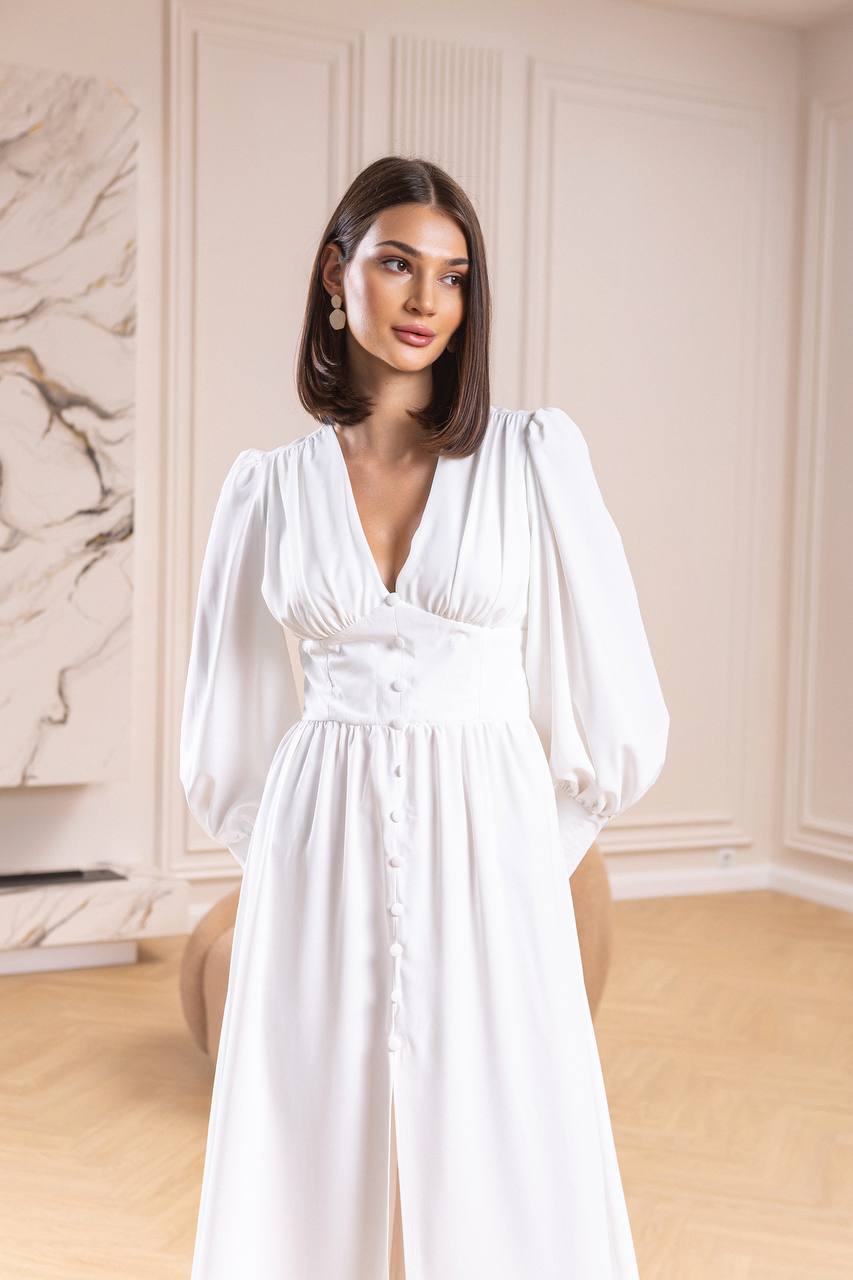 Woman wearing a white dress in an elegant room with marble wall.