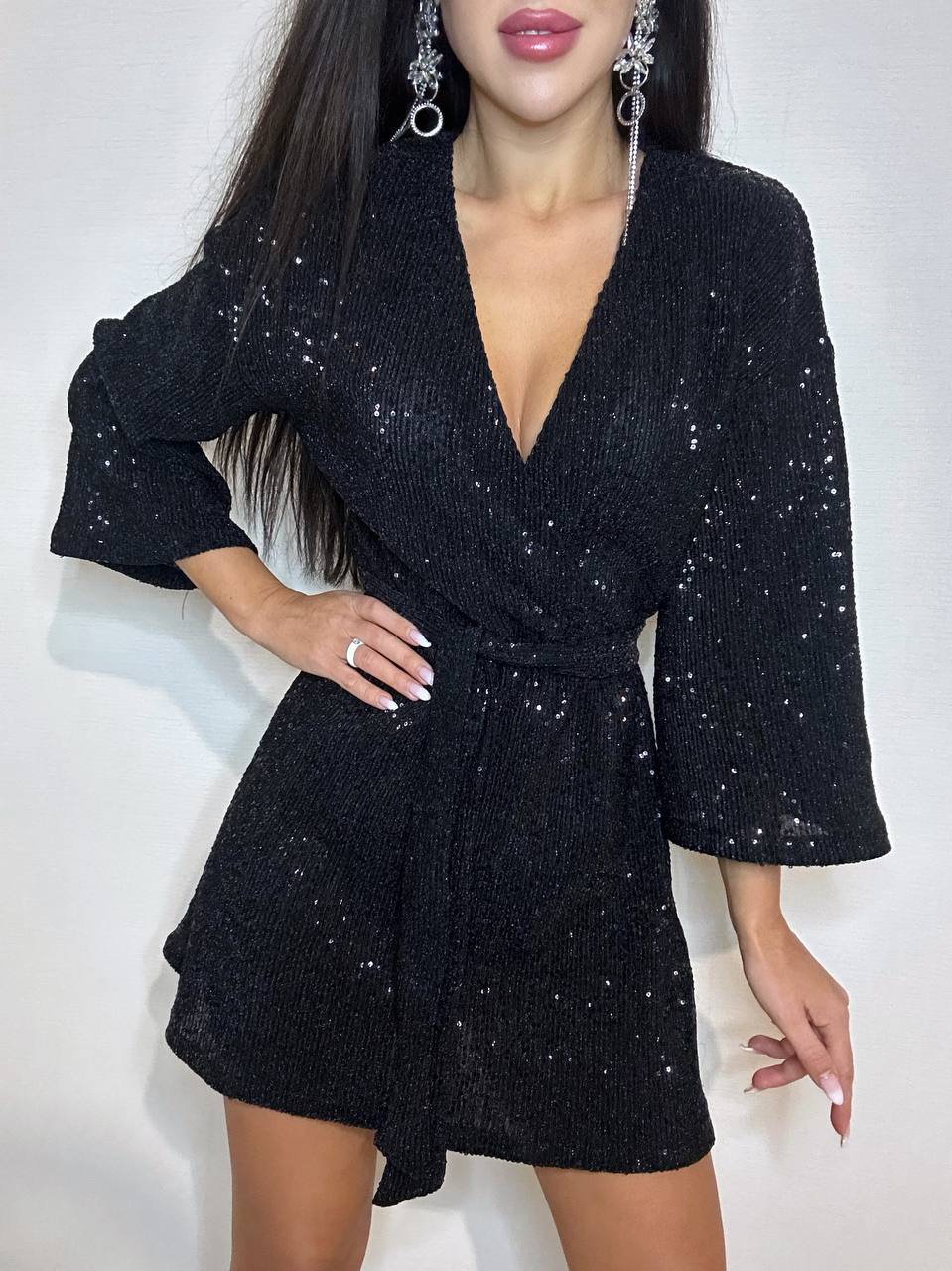 Black sequin dress worn by a model on a white background