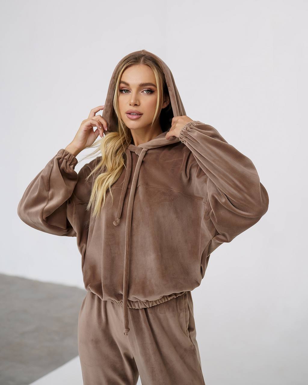 Woman wearing a brown tracksuit against a white background