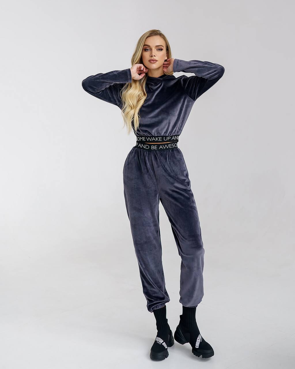Woman wearing a gray velvet tracksuit with text on a white background
