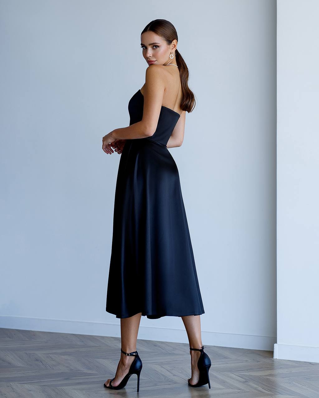 Woman wearing a black strapless dress against a plain background