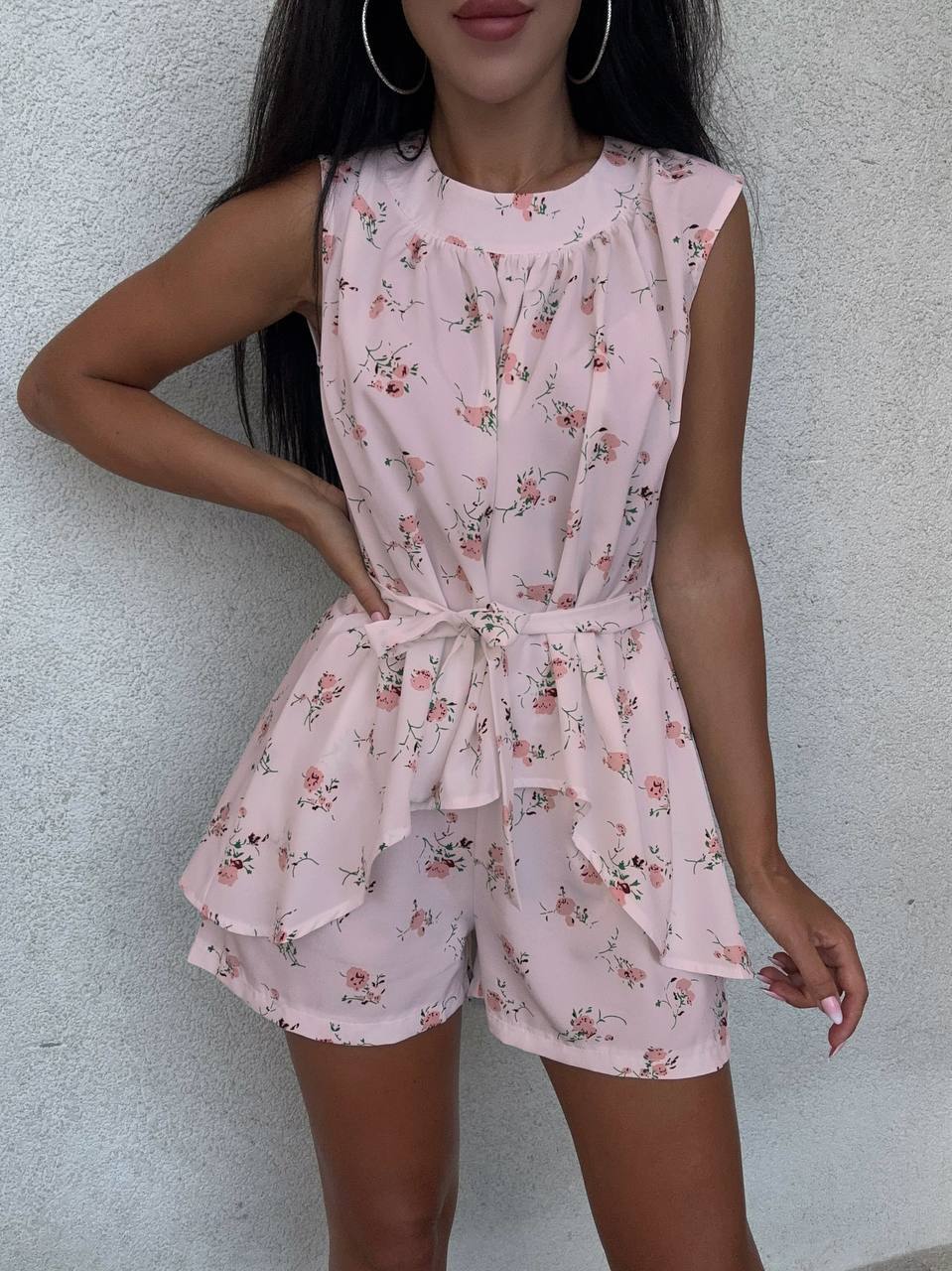 Woman wearing a pink floral romper against a plain background