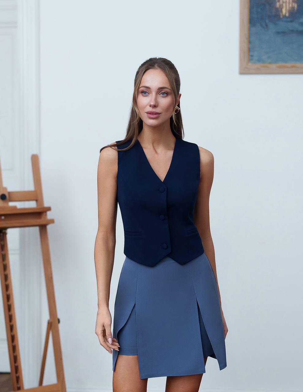 Woman wearing a navy blue sleeveless top and skirt in an indoor setting.