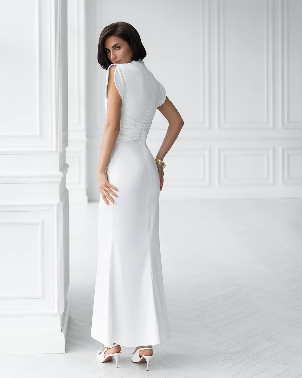 Woman wearing a white dress against a white paneled wall