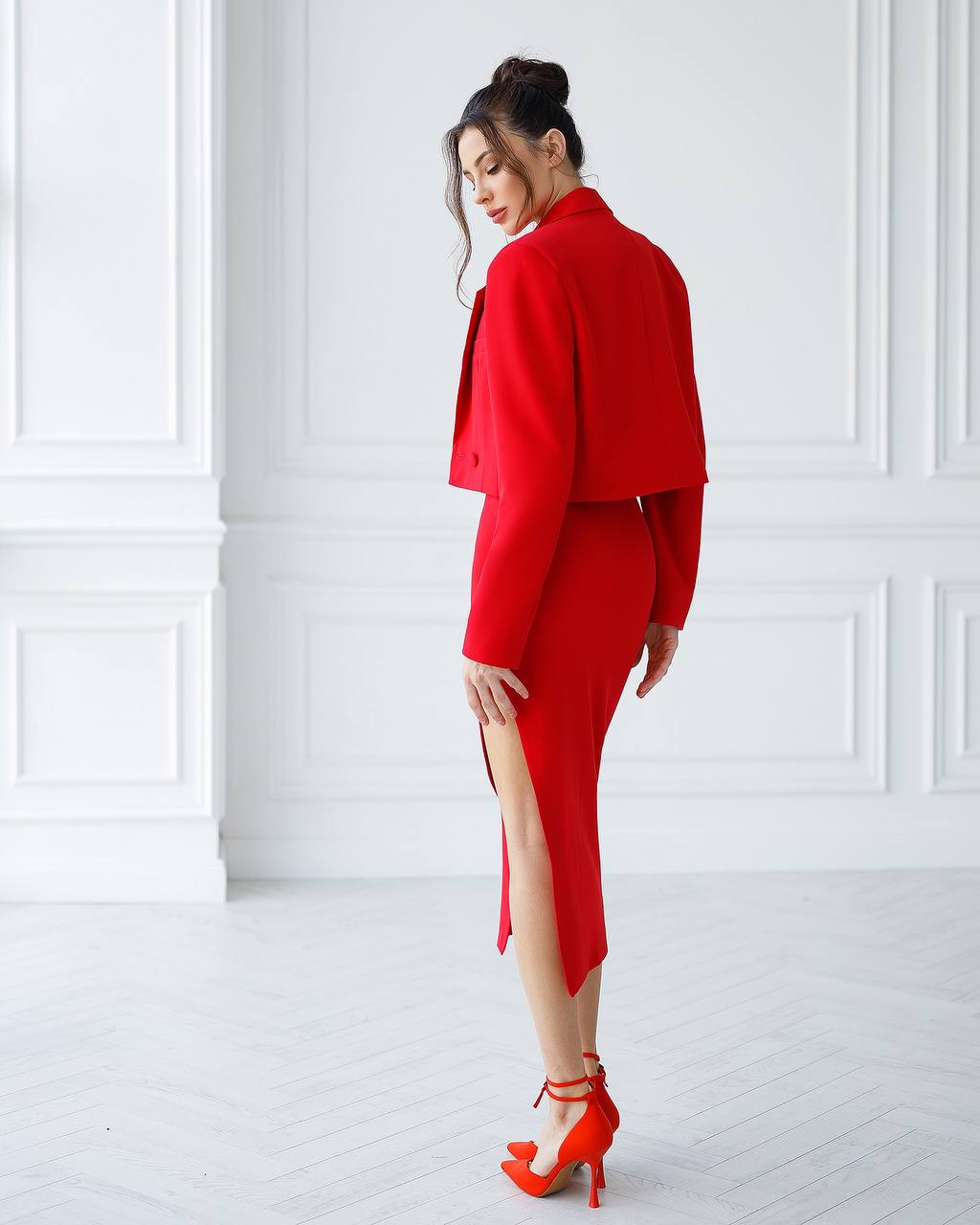 Woman wearing a red outfit with a high slit in a white room