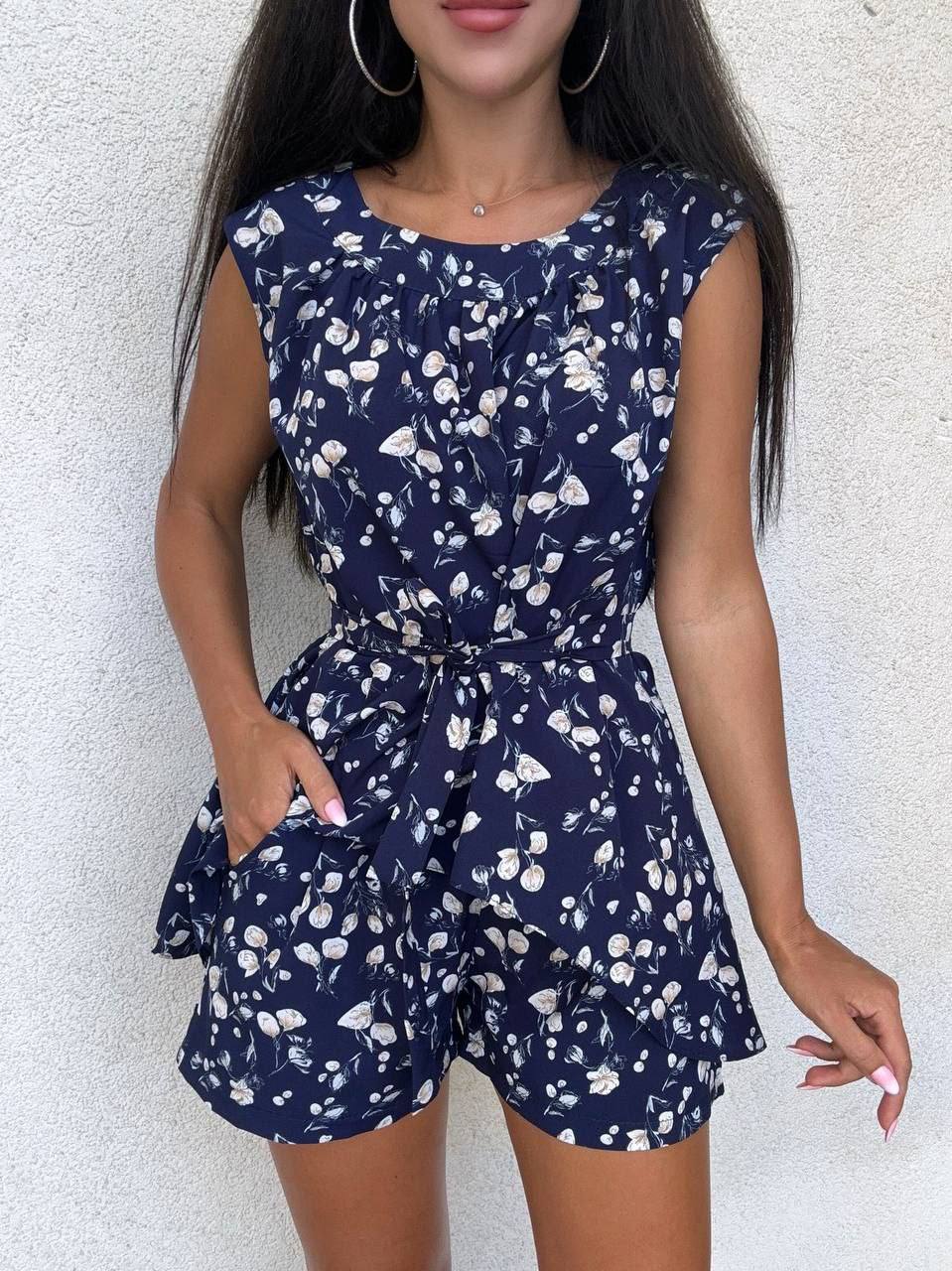 Navy blue romper with white floral pattern worn by a person against a light background