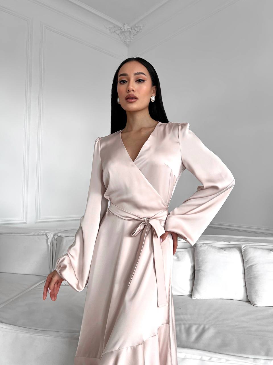 Woman wearing a light pink satin robe in a bedroom setting