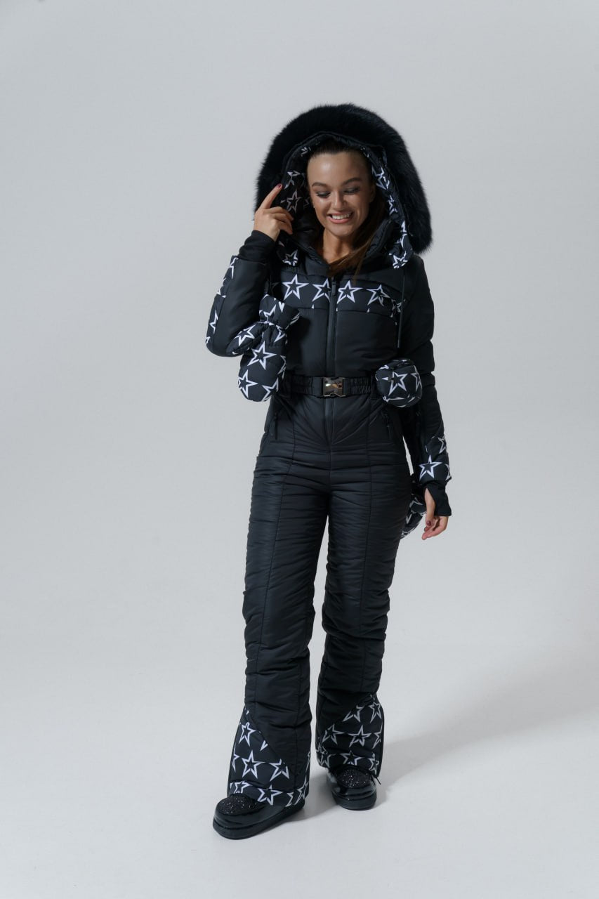 Person wearing a black snowsuit with star patterns on a white background