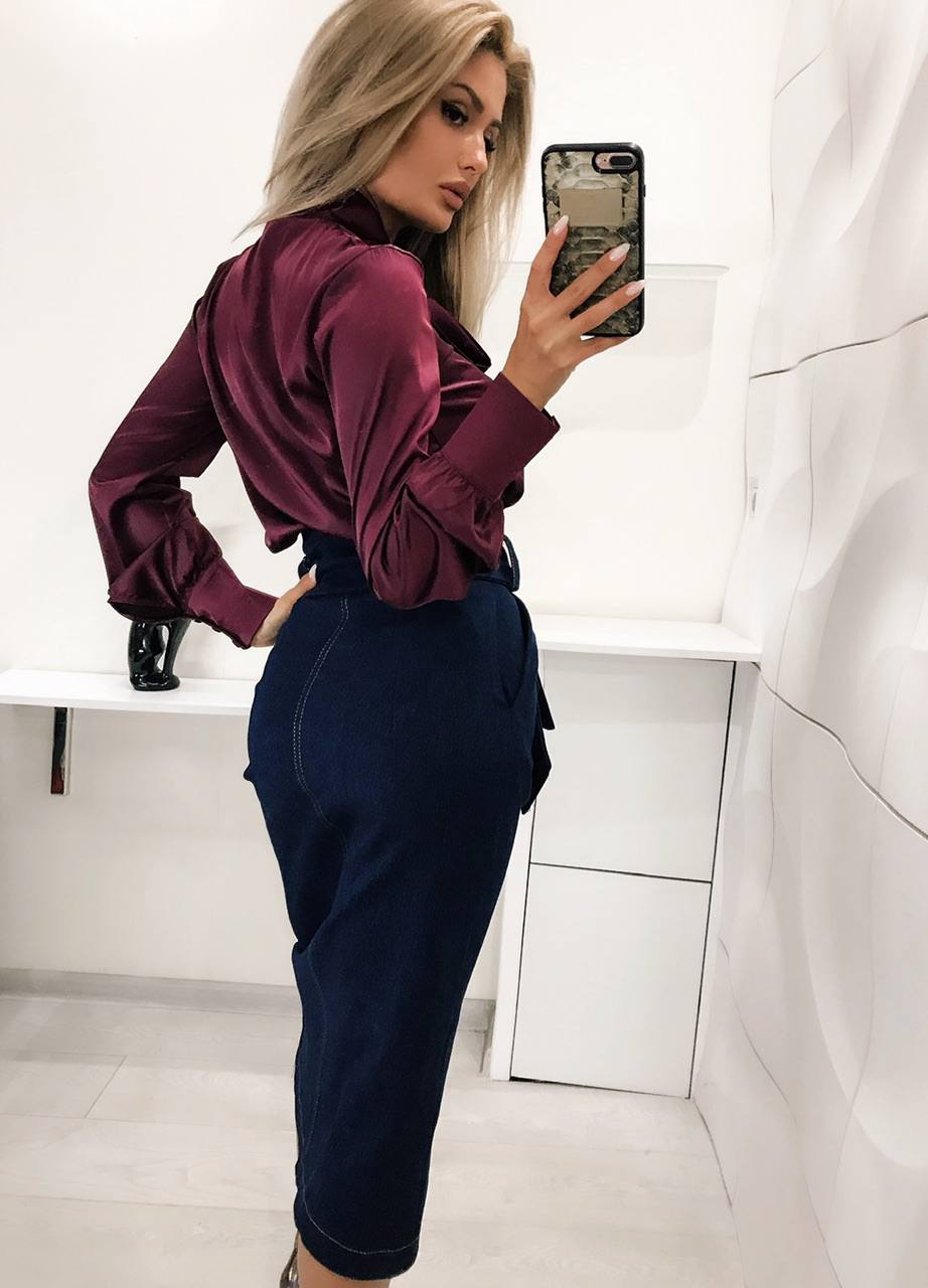 Woman taking a mirror selfie wearing a burgundy blouse and navy pants in a bathroom.