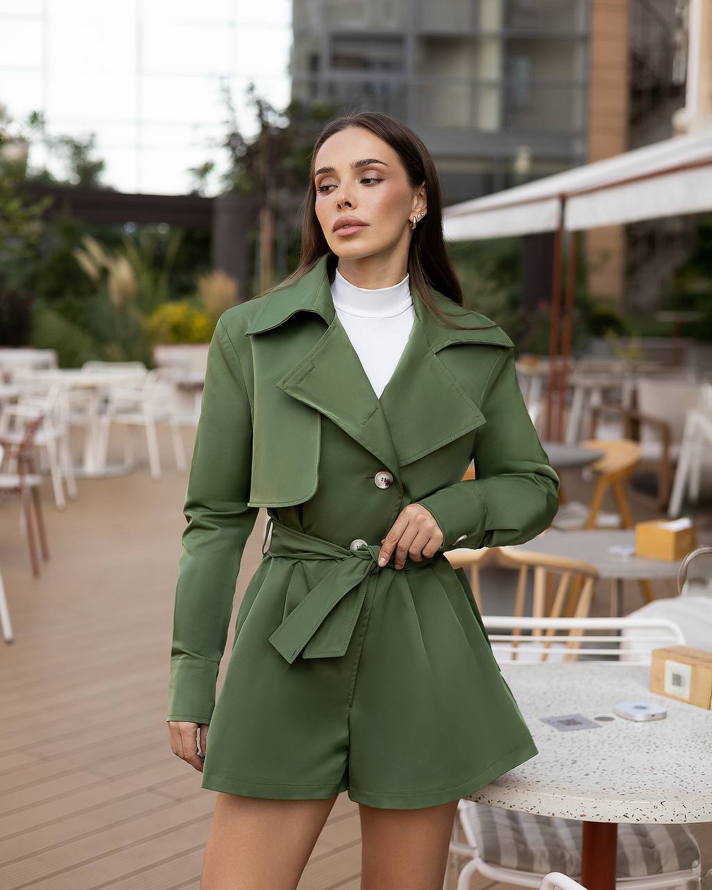 Woman wearing a green coat and shorts set in an outdoor setting
