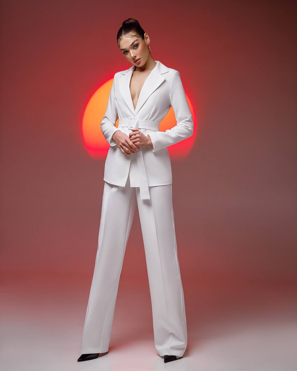 Woman wearing a white suit against a pink background