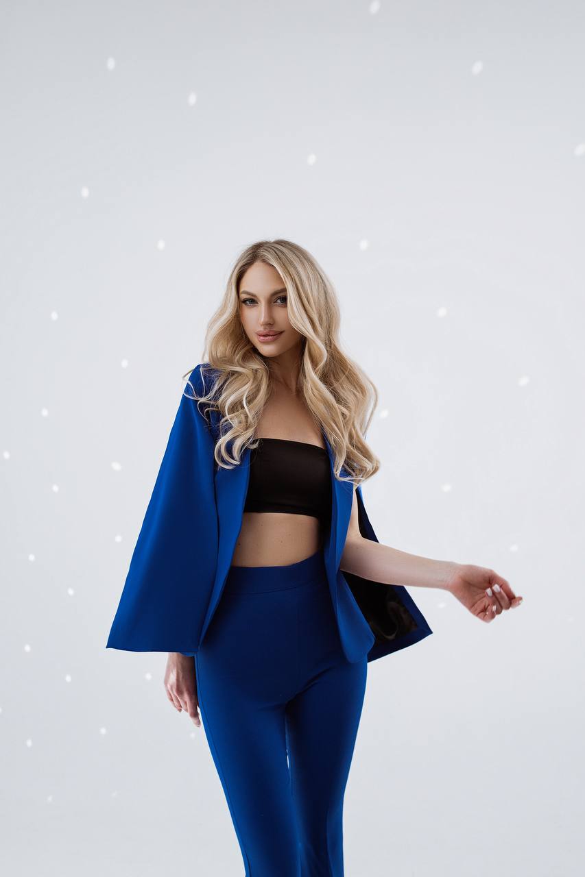 Woman wearing a blue outfit with a black top against a light gray background