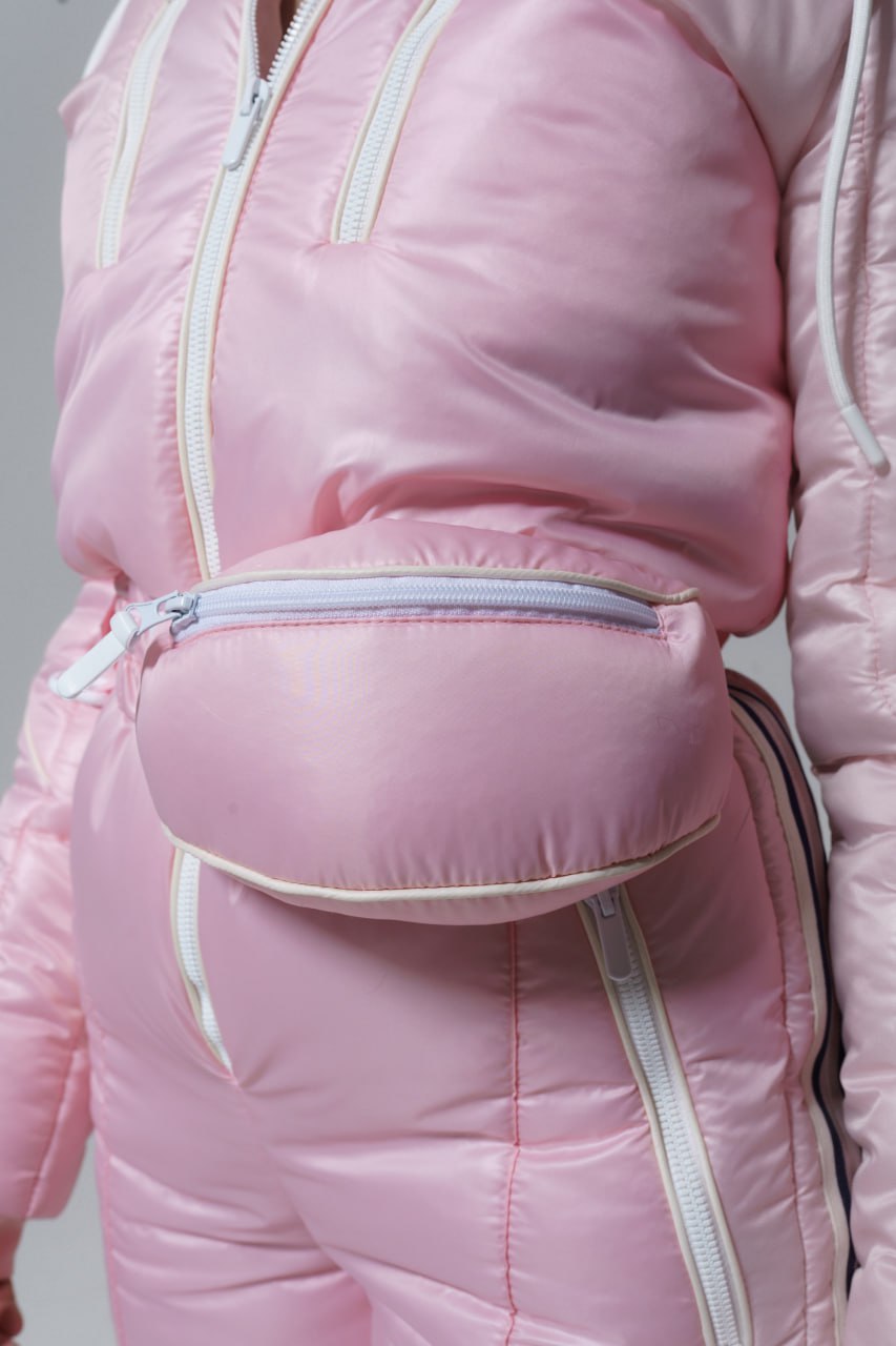 Person wearing a pink puffer jacket with a matching pink pouch on a plain background