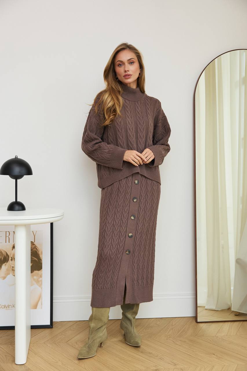 Woman wearing a brown cable knit dress standing in front of a mirror.