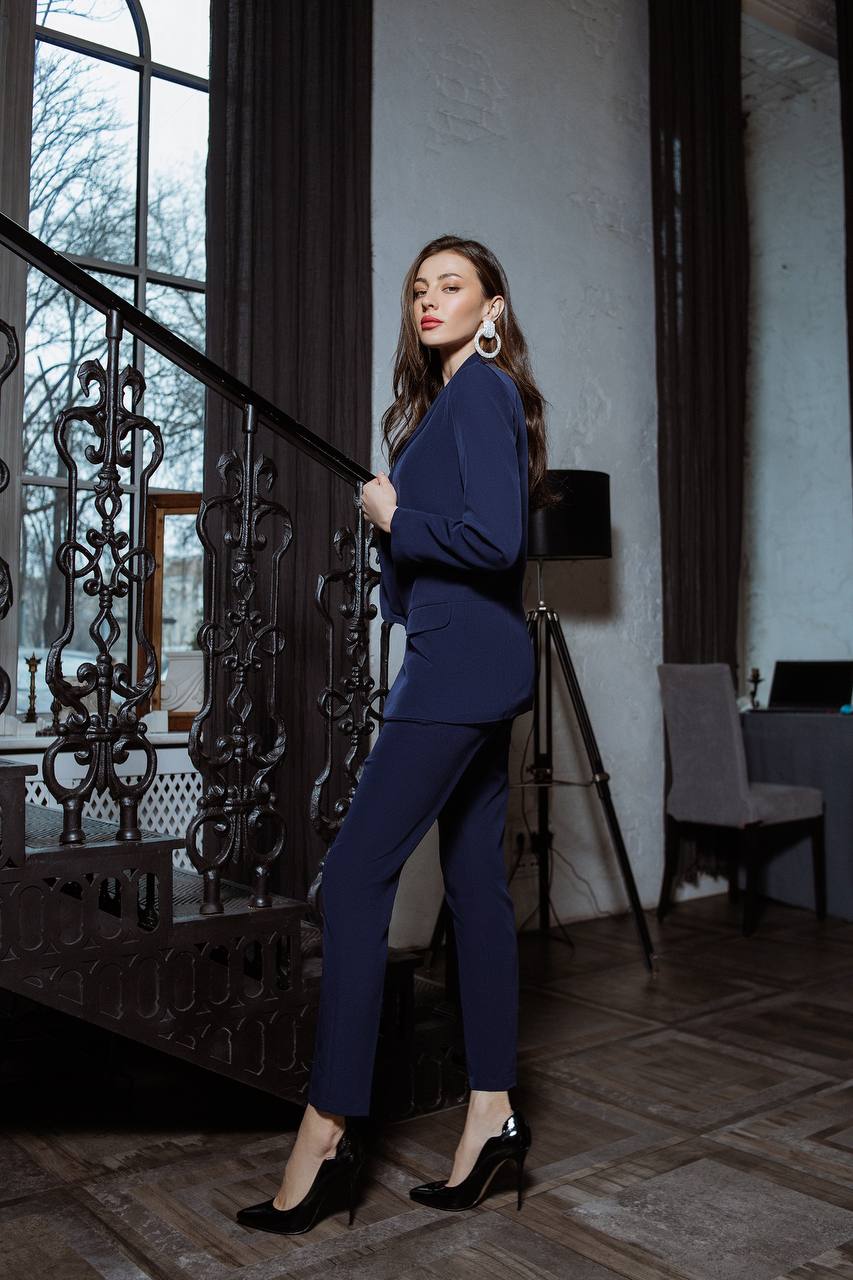 Woman in a navy blue outfit standing in an elegant interior setting.