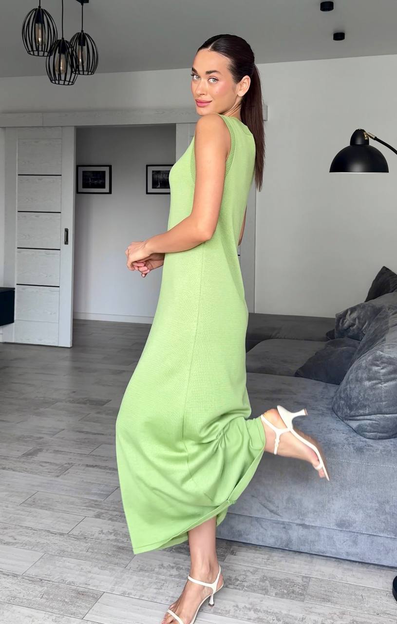 Woman in a green dress standing in a modern living room.