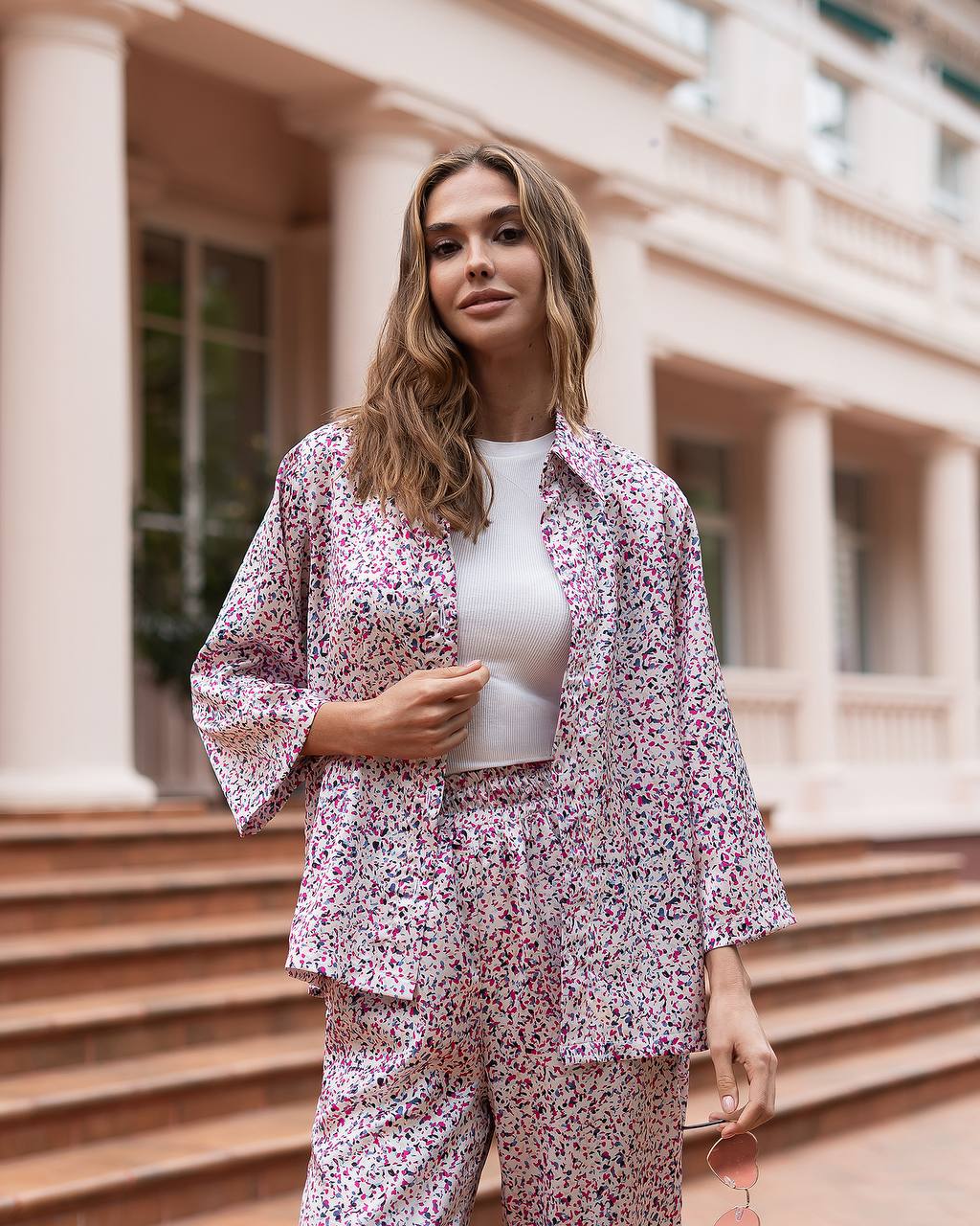 Woman wearing a floral outfit standing on steps in front of a building