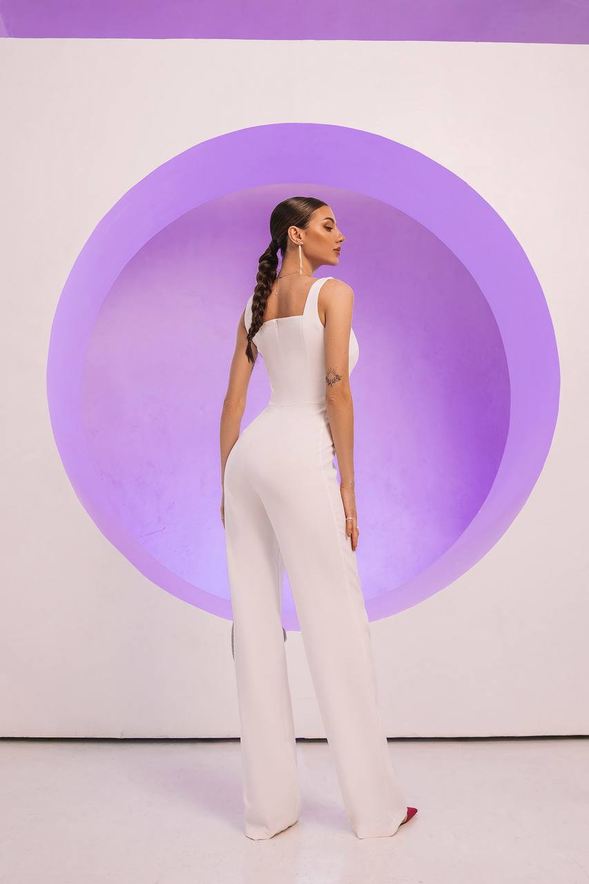 Woman in a white jumpsuit standing against a purple circular background
