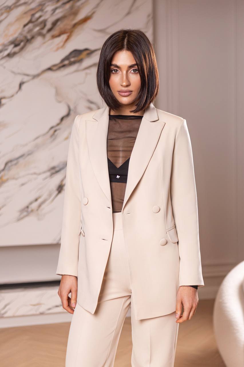 Woman wearing a beige suit with a marble wall background