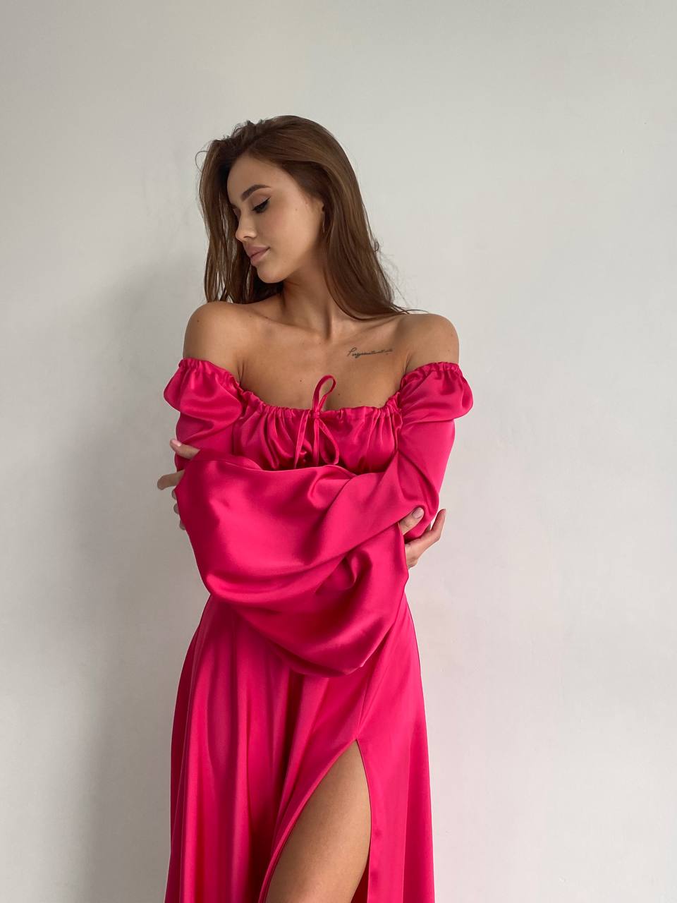 Woman wearing a pink off-shoulder dress against a plain background