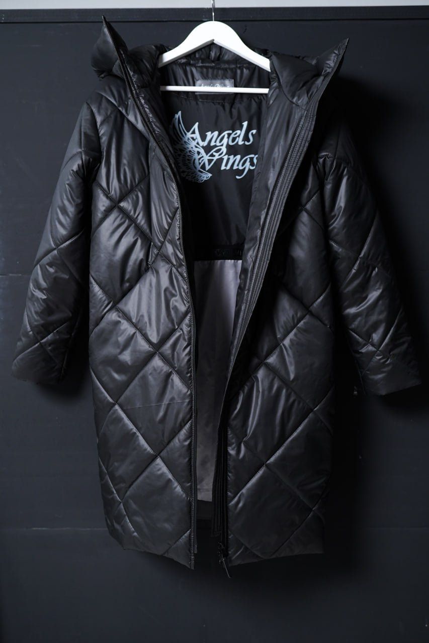 Black quilted jacket on a hanger against a dark background
