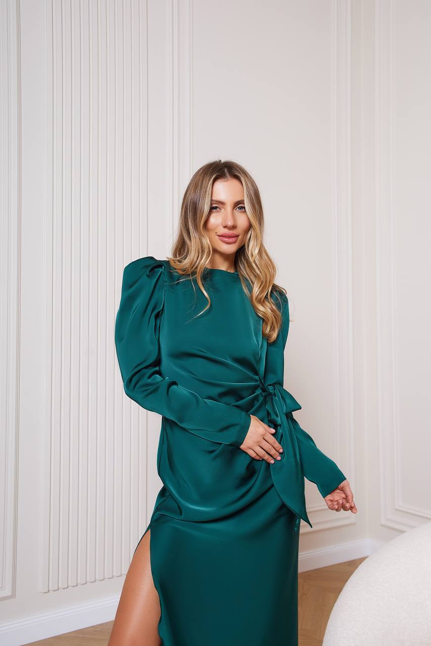 Woman wearing a green dress with a white wall background