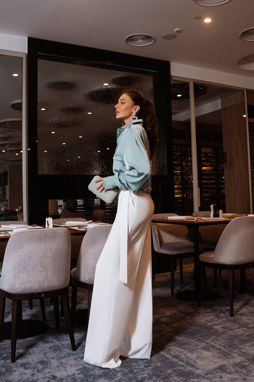 Woman in a stylish outfit standing in a modern restaurant.