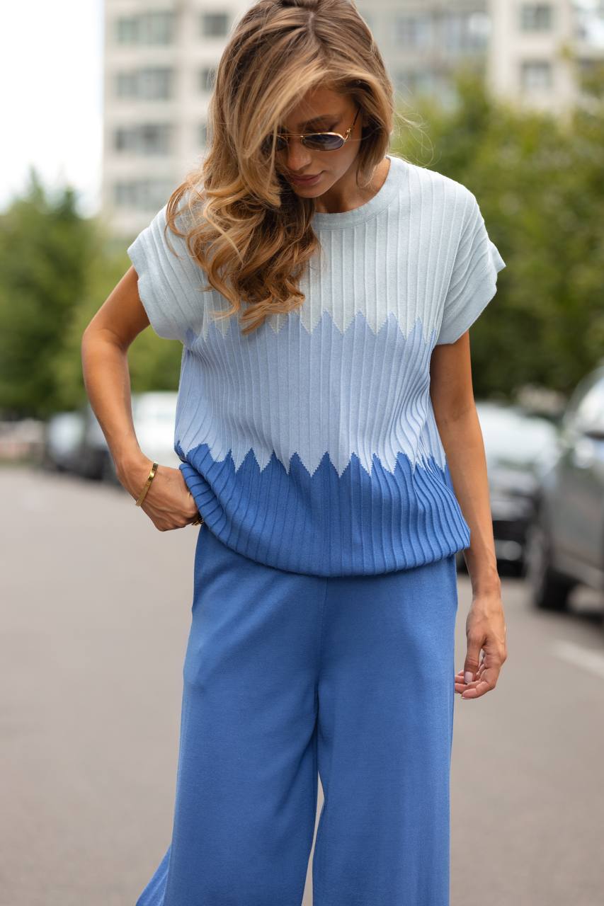 Woman wearing a blue and white gradient sweater with wide-leg pants on a street.